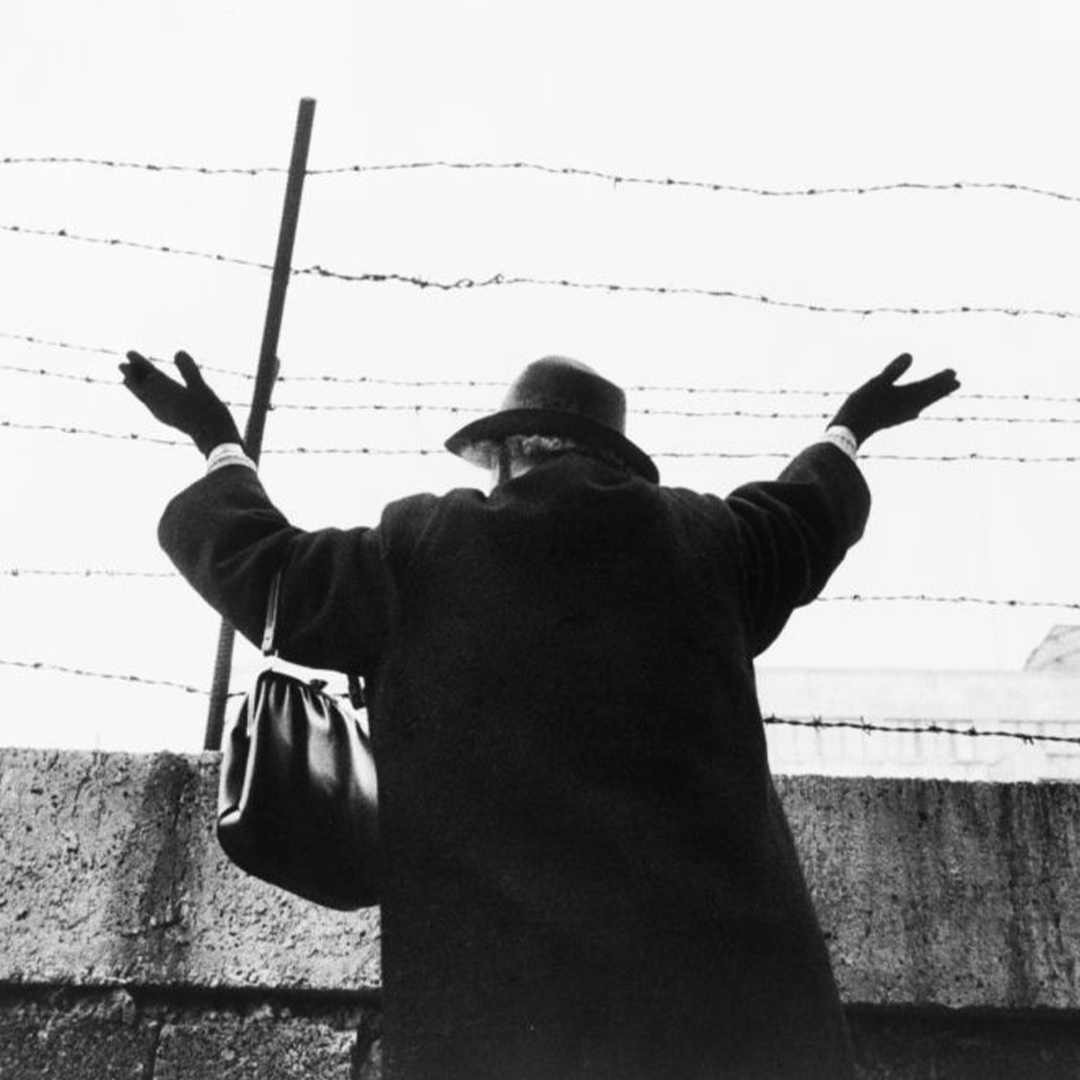 Une femme sur le mur de Berlin fait signe à sa famille et ses ami·e·s restés à l’Est en 1961.