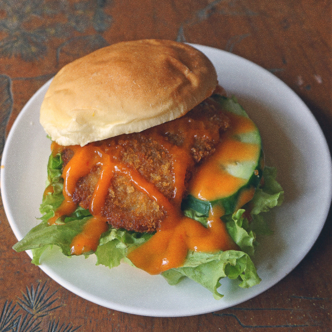 Un Katsu Burger en contre-plongée dans une petite assiette blanche.