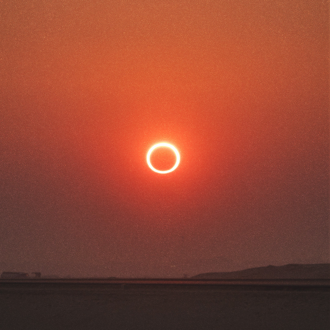 Éclipse annulaire dans un ciel rougeâtre.