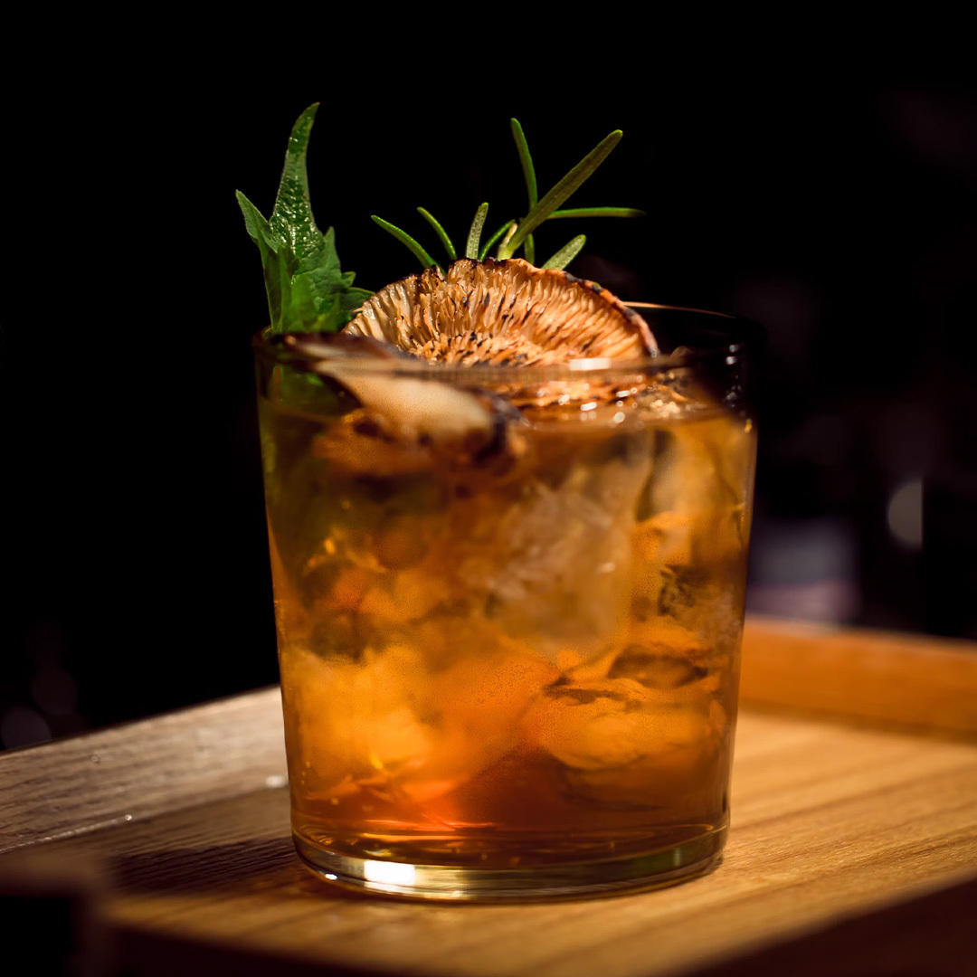 Cocktail sur un comptoir de bar en bois, avec une ambiance tamisée et élégante en arrière-plan.