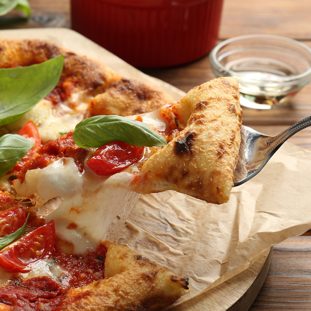 Gros plan d'une pizza Margherita sur planche de bois.