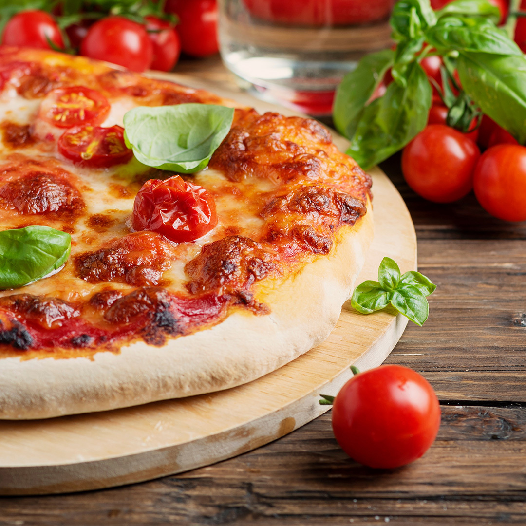 Plan rapproché d’une pizza Margherita sur planche de bois.