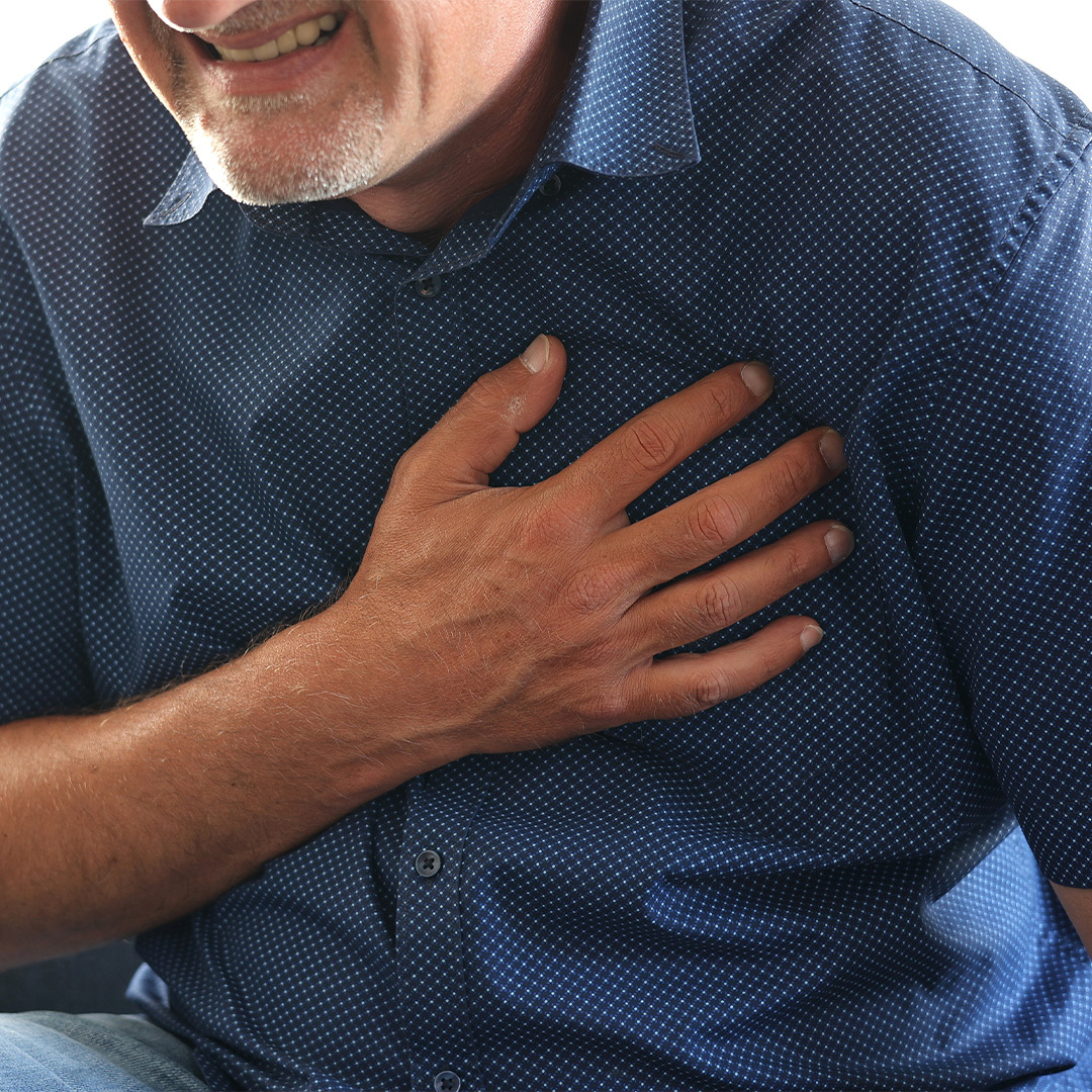 Close-up of a man clutching his heart and grimacing.