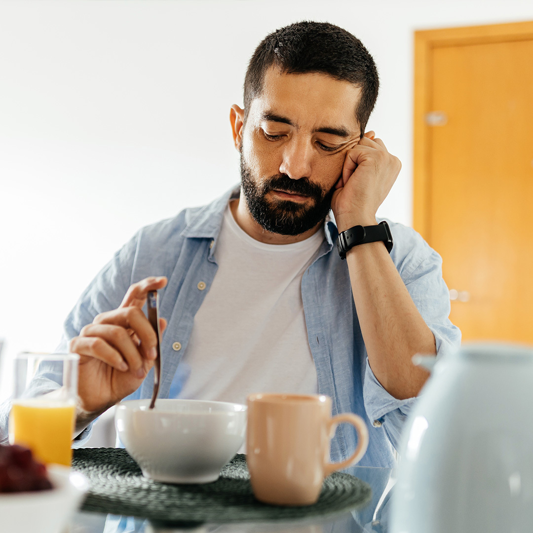 A man seated at a table shows a lack of interest in his food.