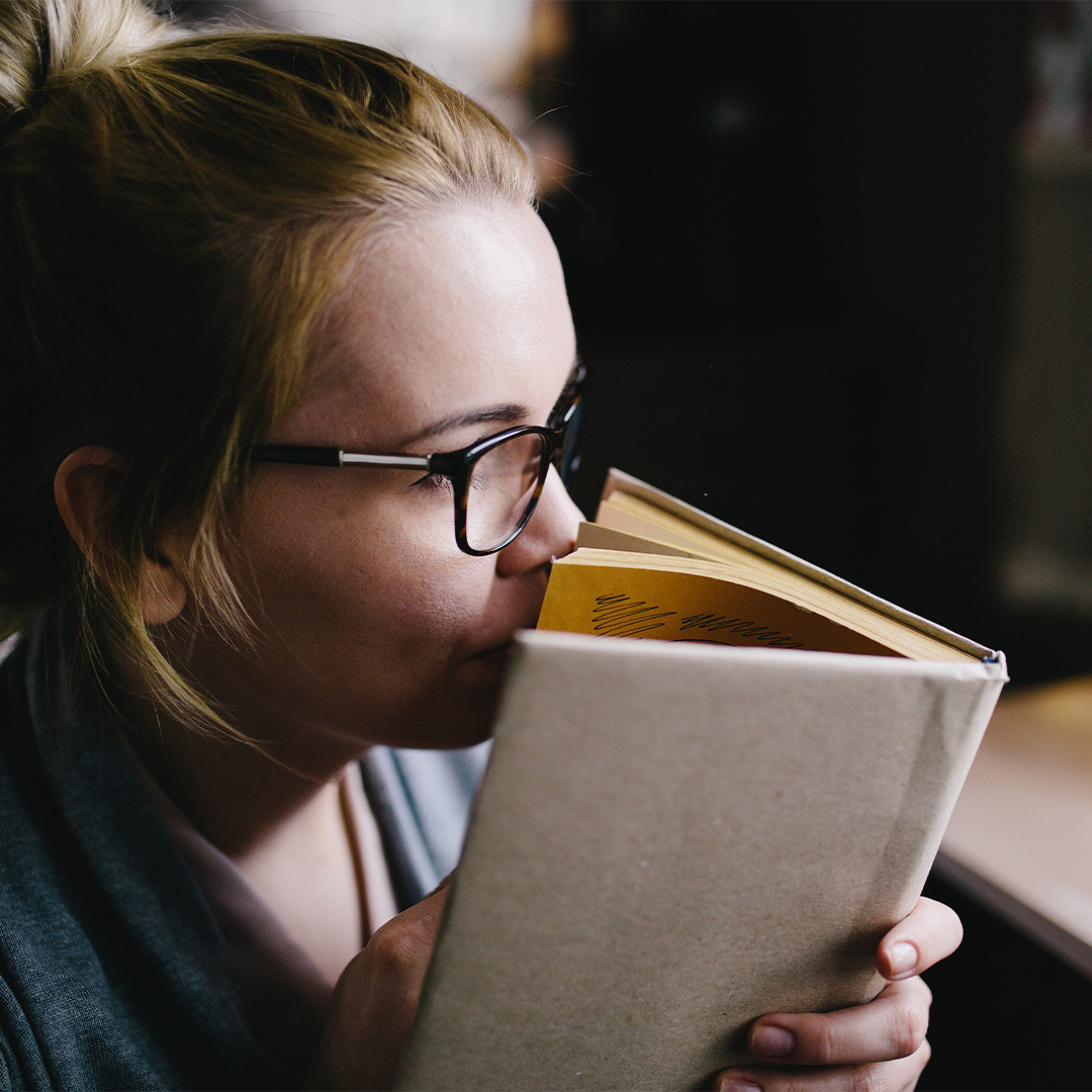 Closeup of woman sniffing the pages of a book.