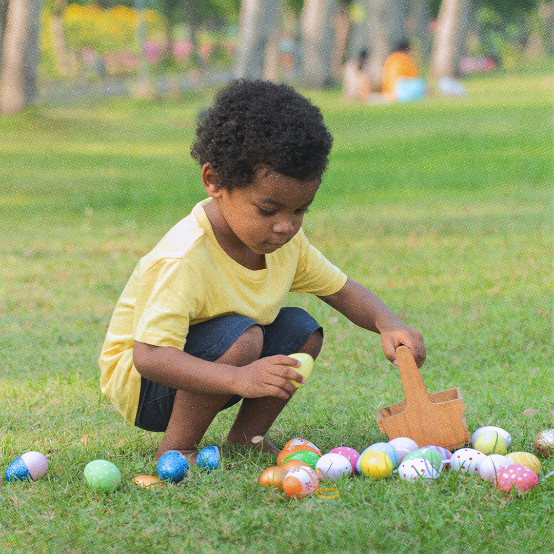 Un petit garçon ramasse des œufs de Pâques dans un jardin.