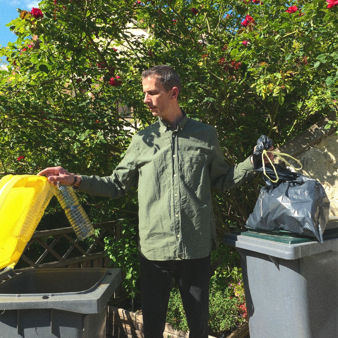 Une personne met des bouteilles en plastique dans un récipient jaune et des ordures dans un sac dans un récipient vert.