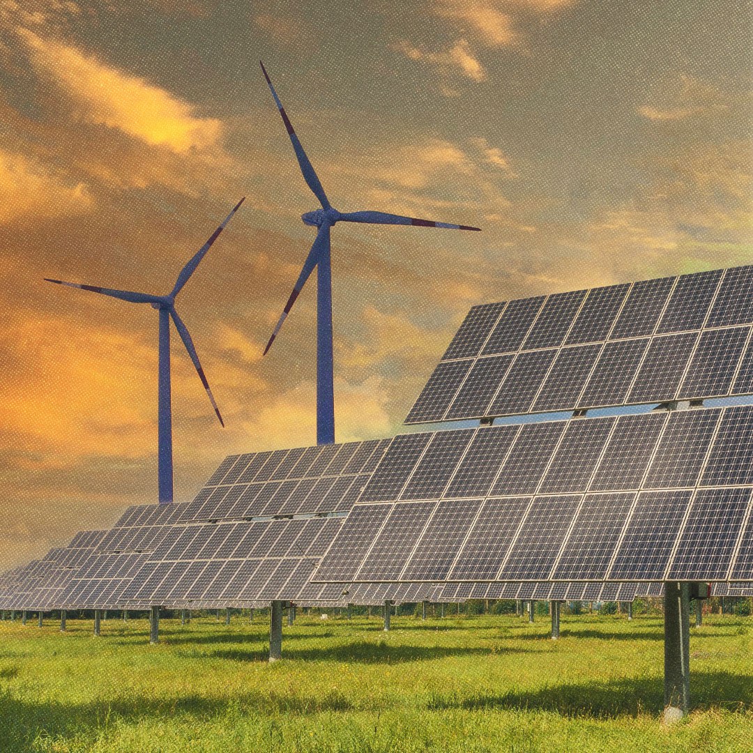 Panneaux solaires à l’avant-plan et deux éoliennes en arrière-plan sur fond de ciel orangé.