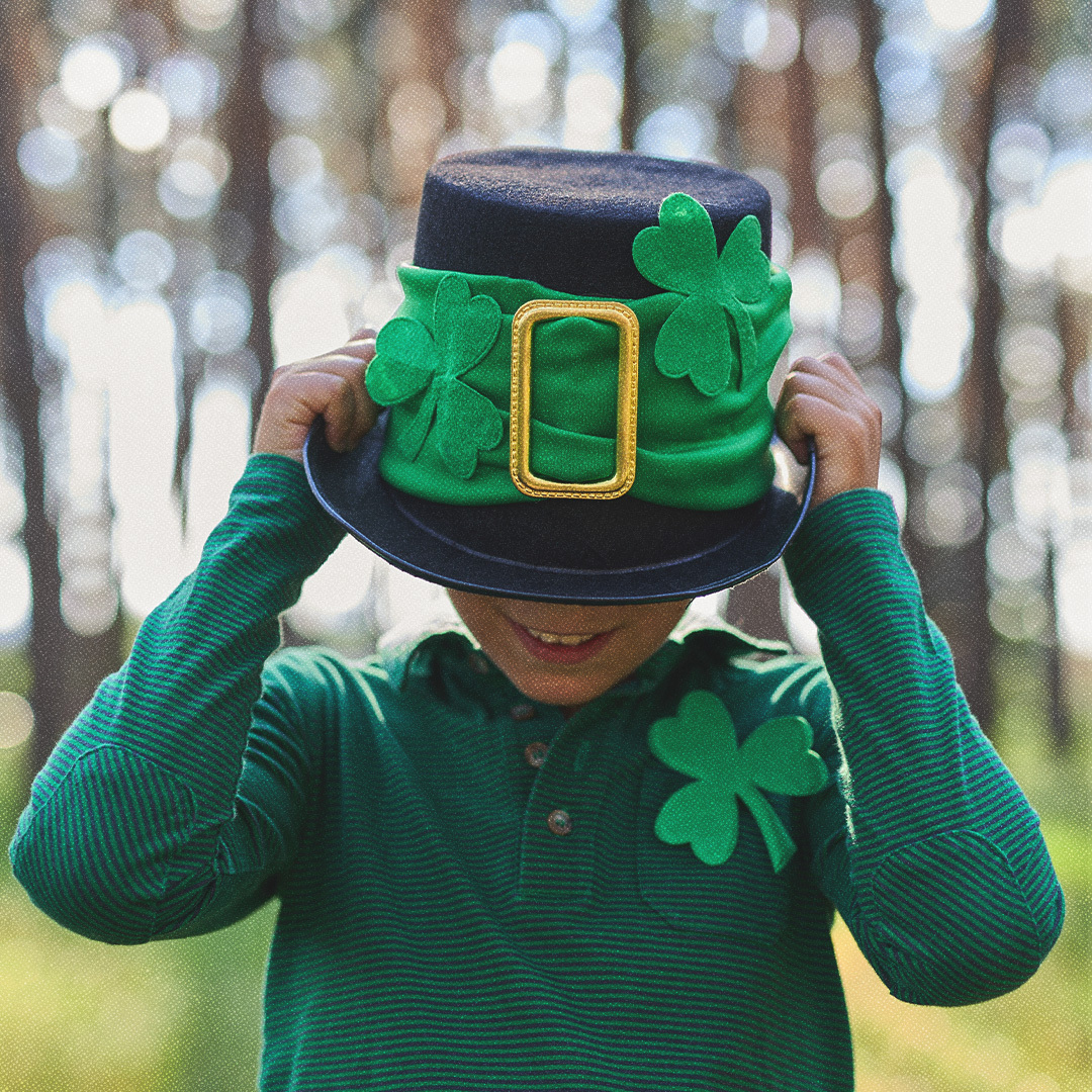 Un enfant vêtu de vert avec un chapeau trop grand pour lui à l’effigie de la Saint-Patrick.