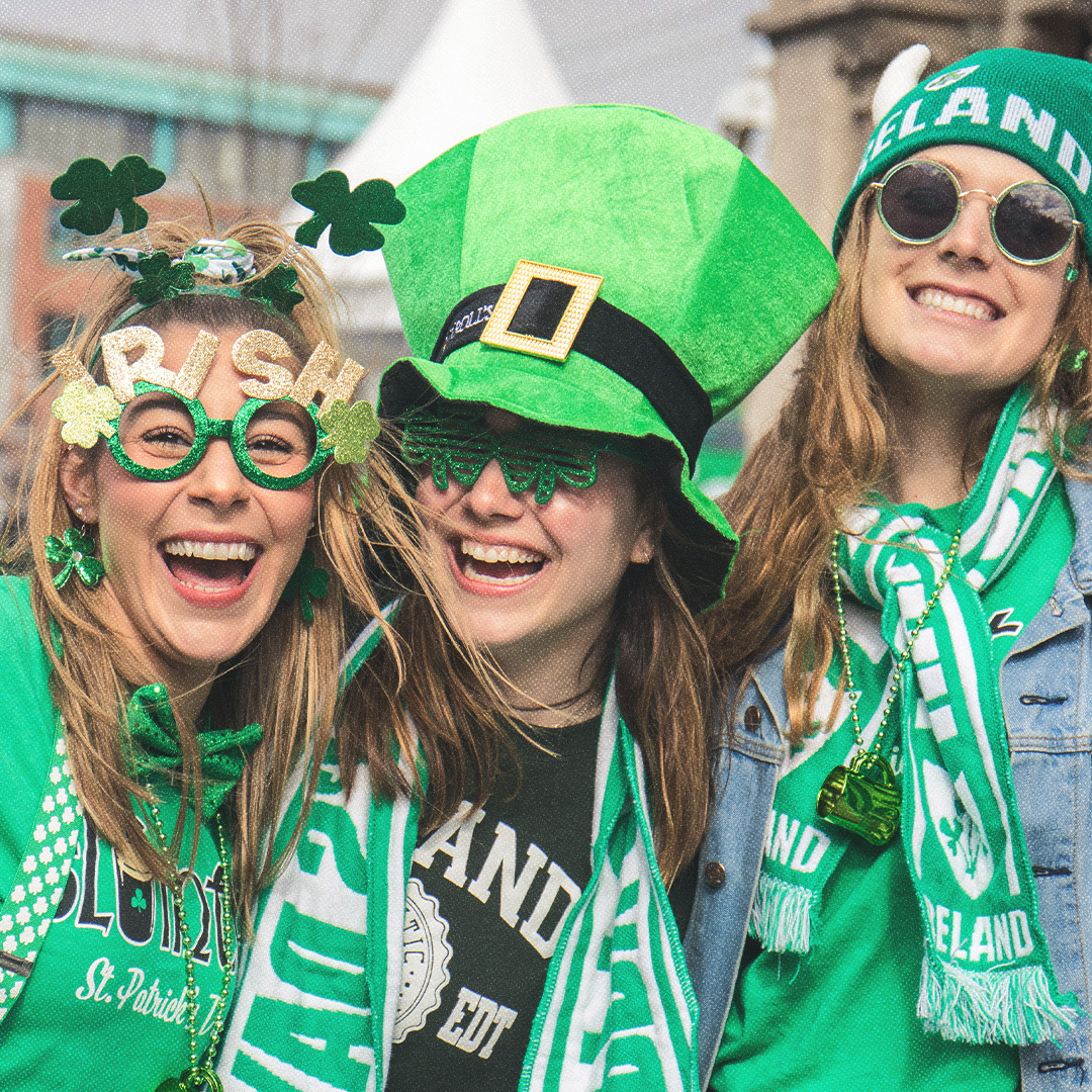 Trois personnes vêtues de vert célébrant la Saint-Patrick dans la rue.