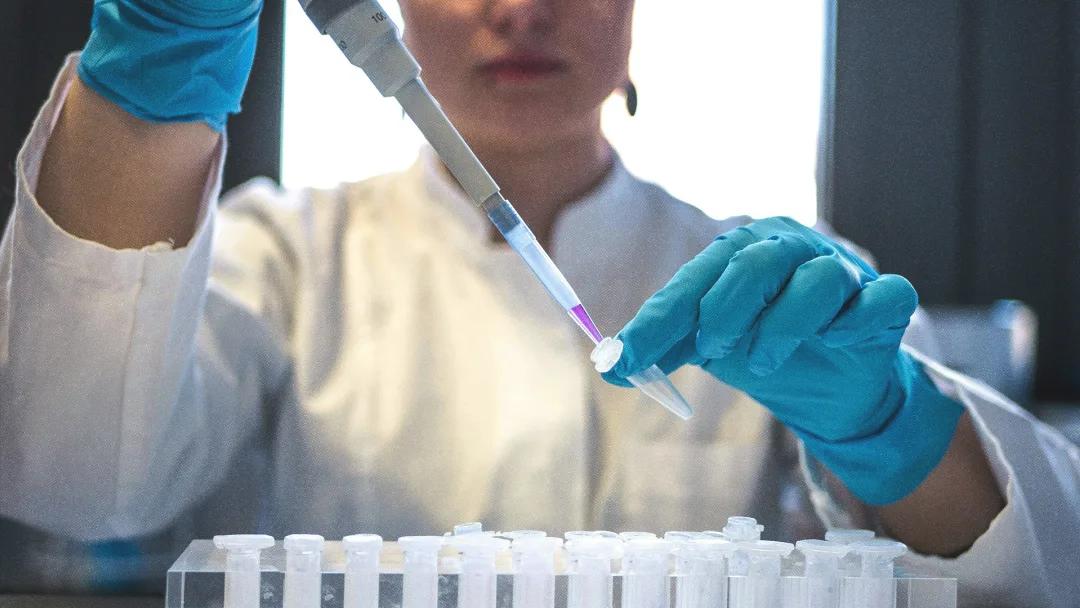 Femme scientifique tenant une pipette dans un laboratoire.